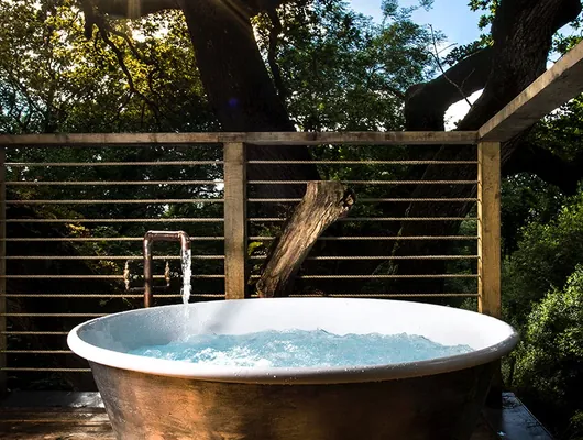 A copper hot tub on the treehouse deck, open to the canopy
