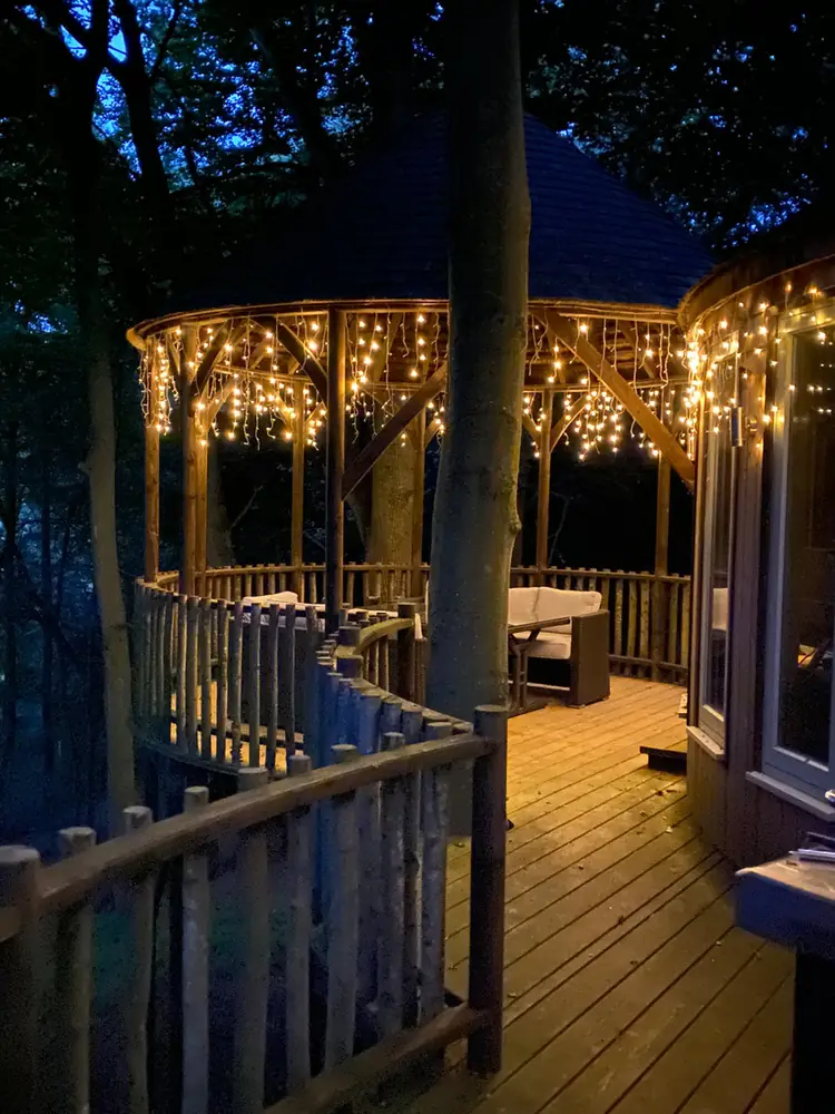 The treehouse deck lit with lights at dusk