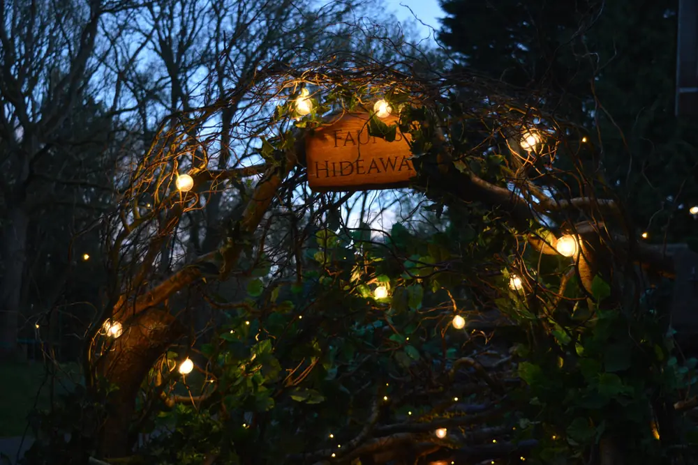 The Faun’s Hideaway sign lit among the trees at night