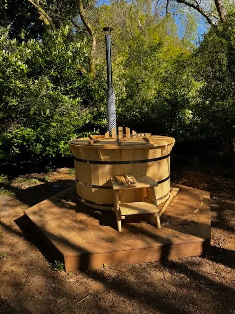 The wood-fired hot tub beneath the trees